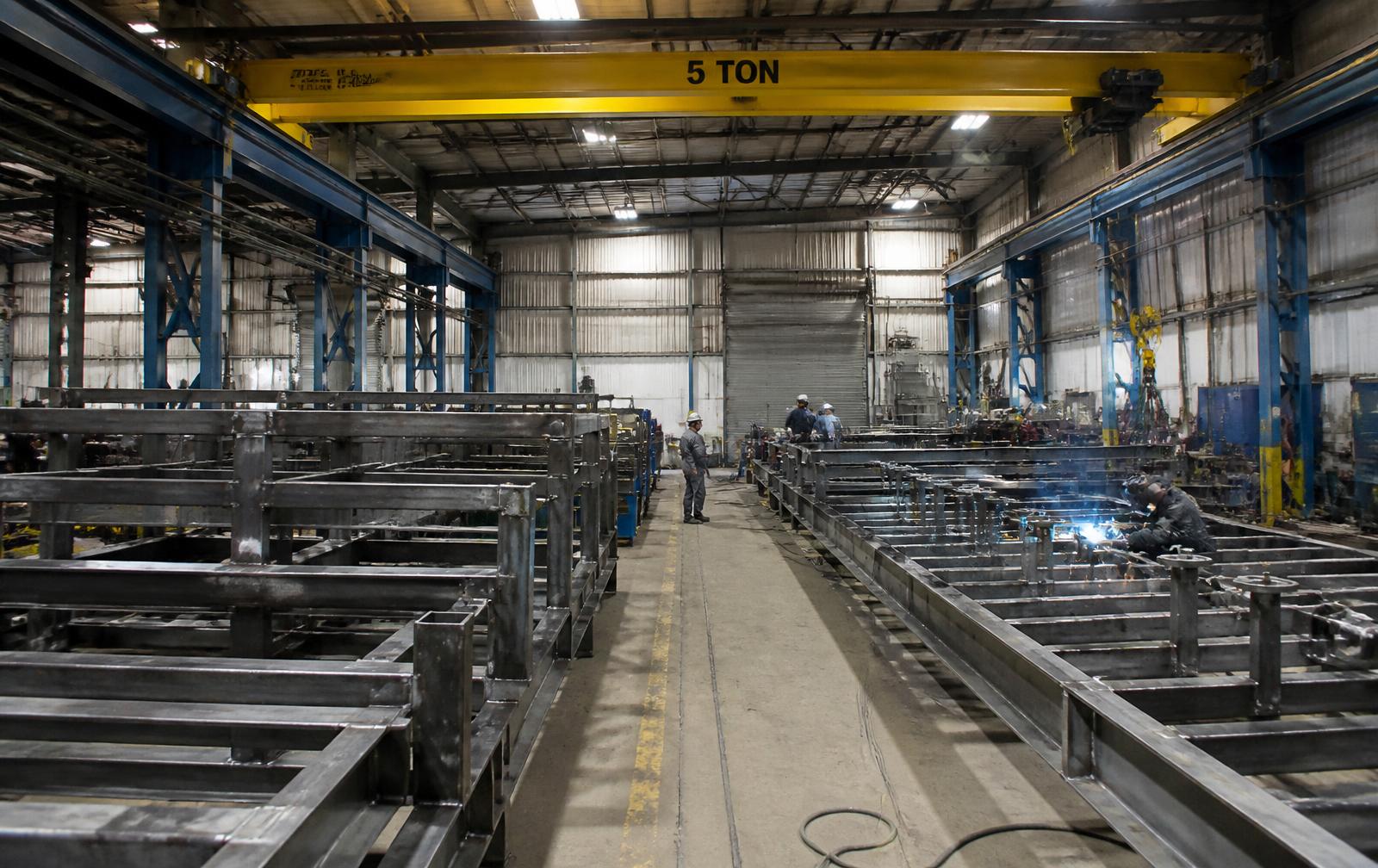 Fabrication workshop with overhead crane and steel skid frames under assembly